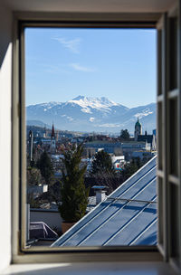 Buildings against sky seen through window