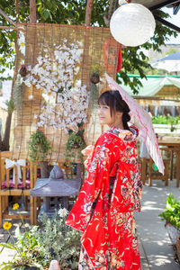 Side view of young woman standing against plants