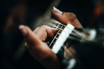 Close-up of cropped hand playing guitar