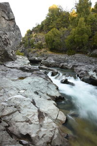 Stream flowing through rocks against sky