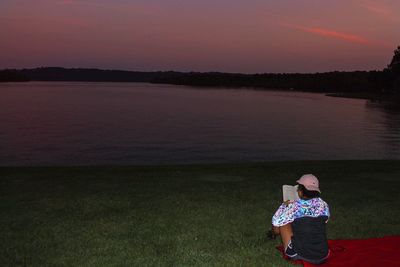 Woman standing on shore against sky during sunset