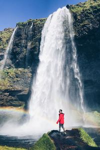 Man standing against waterfall