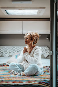 Portrait of young woman sitting on bed at home