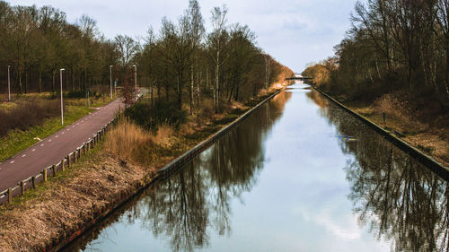 Canal amidst trees against sky