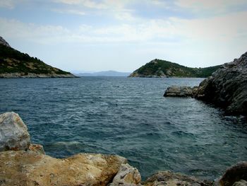 Scenic view of sea by mountains against sky