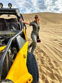 Full length of woman standing on beach buggy at desert