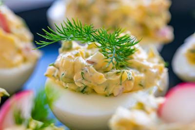 A close up image of freshly prepared boiled eggs filled with mayo, onions, egg and radish garnish