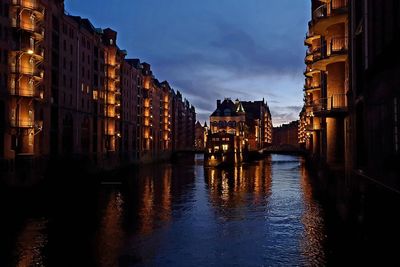 Canal amidst buildings in city at night