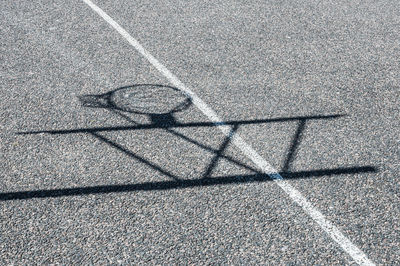 Shadow of basketball hoop on pavement