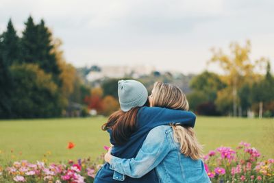 Rear view of couple on field against sky