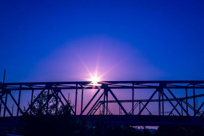 Low angle view of silhouette bridge against blue sky