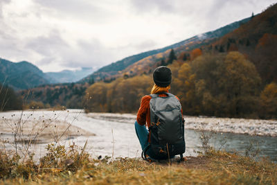 Rear view of man looking at mountains against sky