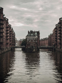 River amidst buildings in city against sky