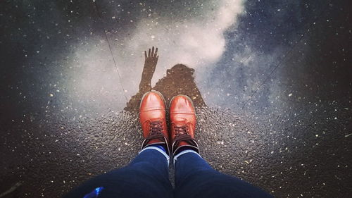 Low section of woman standing by puddle on street