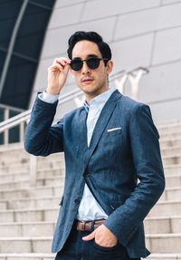 Young man wearing sunglasses standing against brick wall