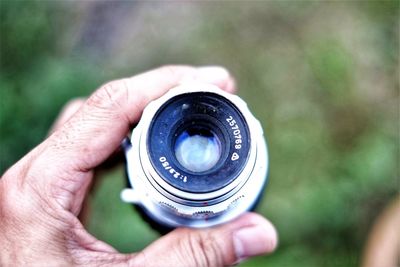 Close-up of hand holding camera lens outdoors
