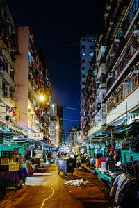 Illuminated street amidst buildings in city at night