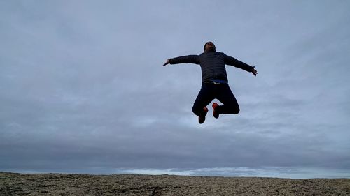 Full length of man jumping in sea against sky