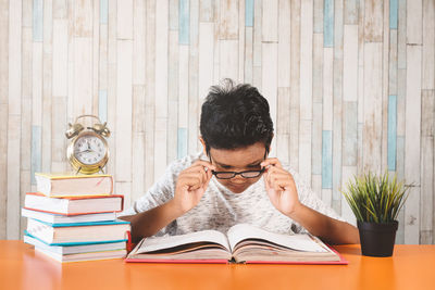 Portrait of young man reading book on table