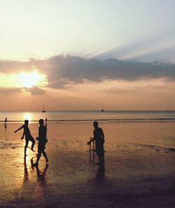 Silhouette of people on beach at sunset