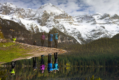 Reflection of people on lake against mountain range