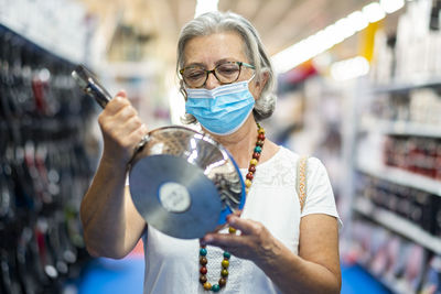 Portrait of senior woman holding cooking pan standing in store