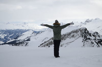 Rear view of man standing on snowcapped mountain