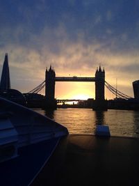 Silhouette bridge over river against sky during sunset