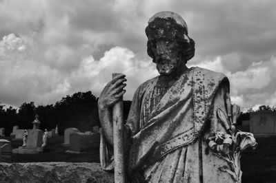 Statue in cemetery against sky