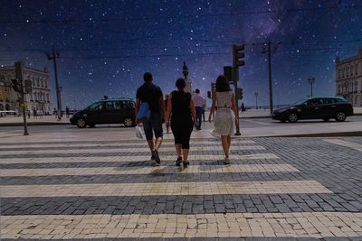 People walking on sidewalk in city at night