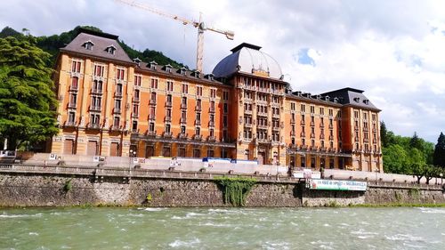 Building by river against cloudy sky