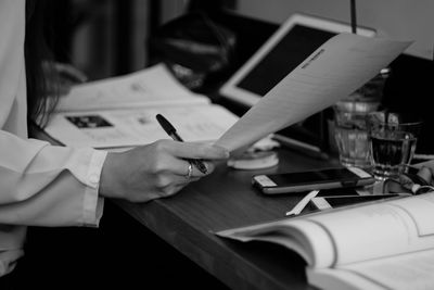 Midsection of woman reading book on table