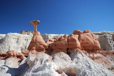 Low angle view of rocks against clear blue sky