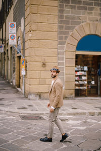 Full length of man standing on footpath by building