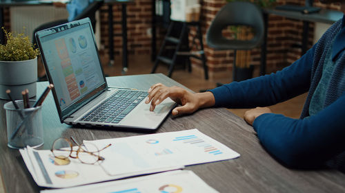 Midsection of man using laptop on table