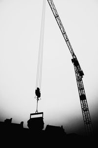 Low angle view of crane at construction site against sky