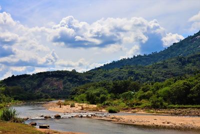 Scenic view of river by mountains against sky