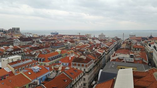 Aerial view of city by sea against sky