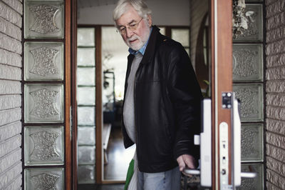 Senior man wearing leather jacket closing door