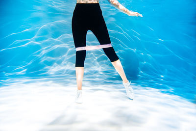 Low section of woman jumping in swimming pool