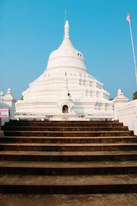 Low angle view of steps of white buddhist temple against blue sky