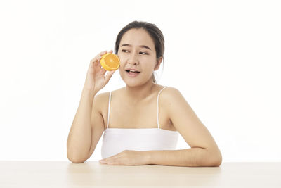 Portrait of woman holding ice cream against white background