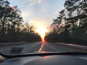 Cars on road against sky during sunset