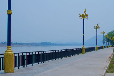 Street light by sea against clear blue sky