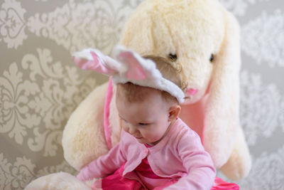 Baby girl sitting with stuffed toy at home