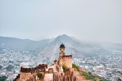 View of tower at jaipur wall against foggy city