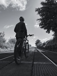 Cyclist holding a bicycle looking up a railway line