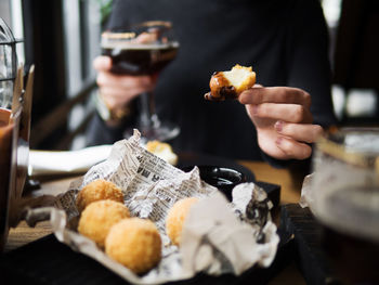 Crop female holding delicious mozzarella cheese ball while sitting at table in cafe with glass of wine