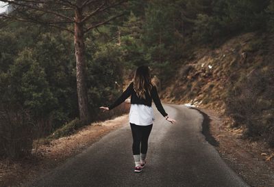 Rear view of man walking on road amidst trees