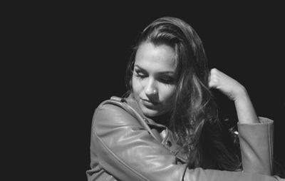 Close-up of young woman against black background